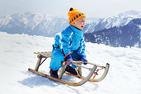 Kind auf Schlitten im Schnee
