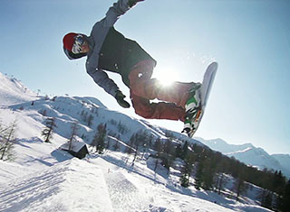 Snowboarder springt über Rampe
